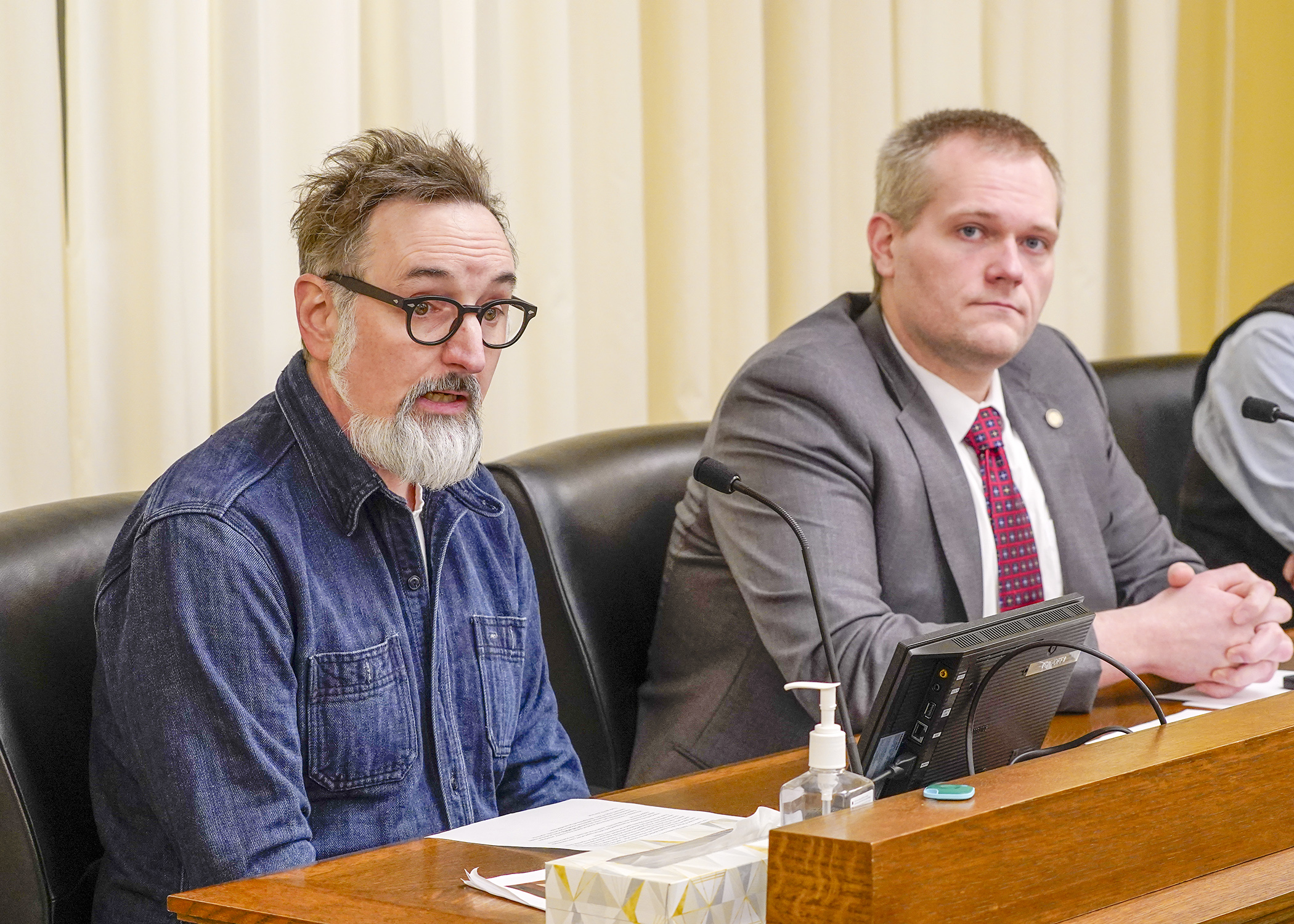 Darrin Rinne, co-owner of Wet Paint Artists’ Materials and Framing, testifies before the House Commerce Finance and Policy Committee March 5 for a bill sponsored by Rep. Bjorn Olson, right, to eliminate Minnesota’s prohibition of paint or pastels containing cadmium. (Photo by Andrew VonBank)